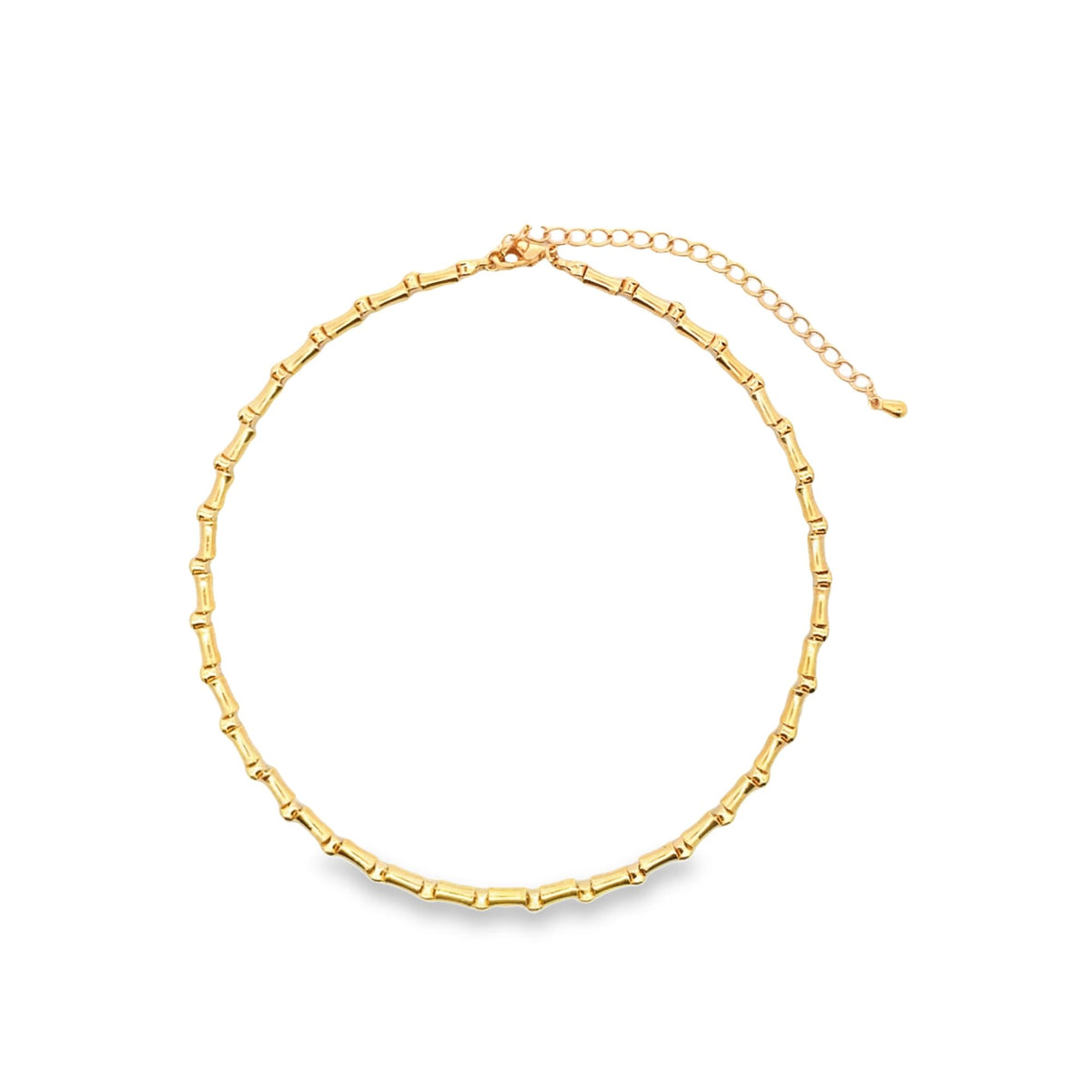 A polished gold bamboo choker necklace rests on a plain white background, highlighting its textured, segmented design.