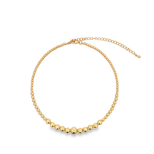 A gold-plated beaded choker necklace with graduated spheres rests against a plain white background.