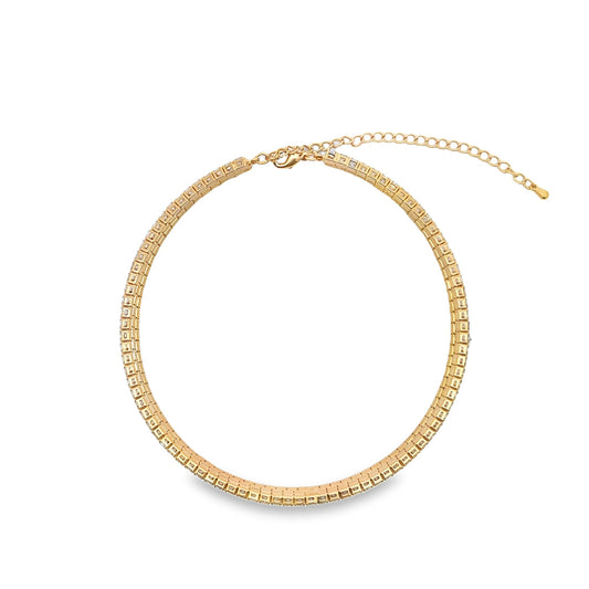 A sparkling gold tennis choker necklace rests in a neat circle against a clean white background.