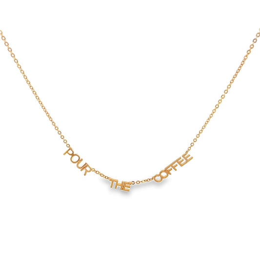 A delicate gold chain necklace features a pendant that spells out the phrase "POUR THE COFFEE" against a clean white background.