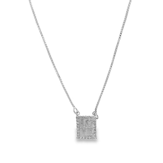 A silver chain necklace displays a rectangular pendant engraved with the words "I LOVE ME" surrounded by small sparkling gemstones.