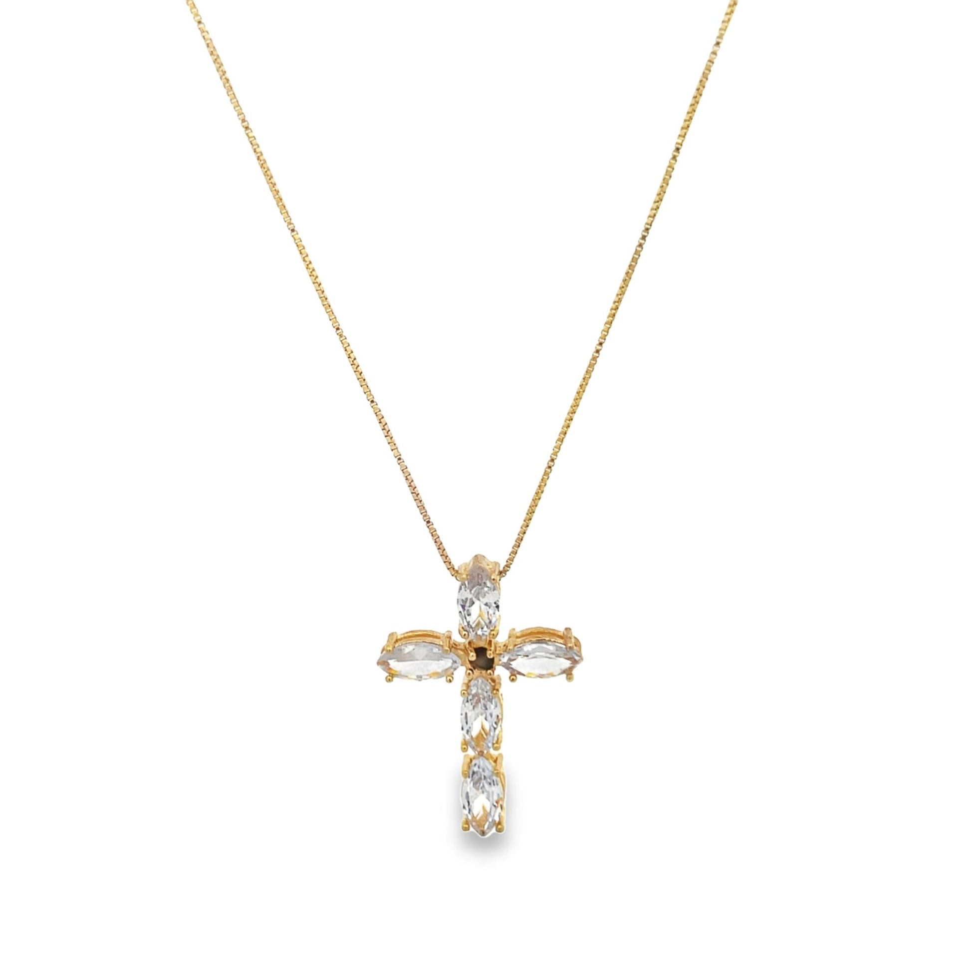 A delicate gold chain holds a sparkling crystal cross pendant against a plain background.