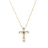 A delicate gold chain holds a sparkling crystal cross pendant against a plain background.