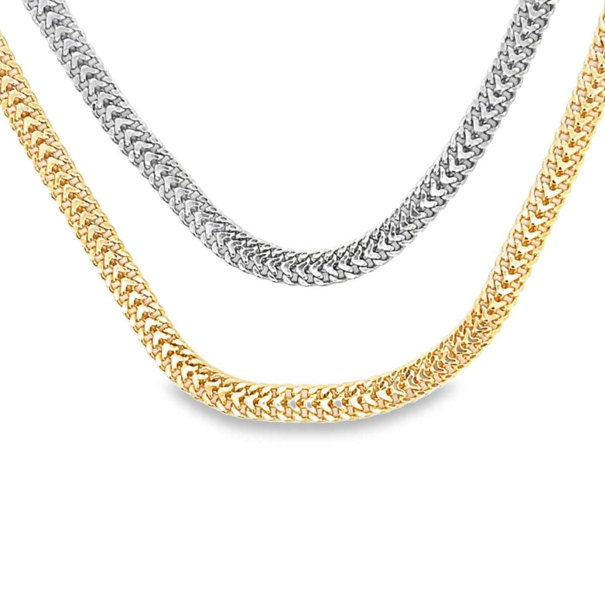 A yellow gold and a white gold Franco chain necklace rest side-by-side on a white background.