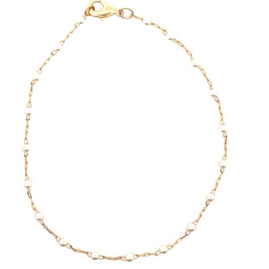 A delicate gold chain bracelet features evenly spaced small pearls against a plain white background.
