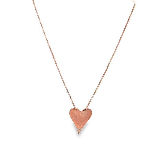 A delicate rose gold chain necklace features a textured heart pendant adorned with three small diamonds at the tip.