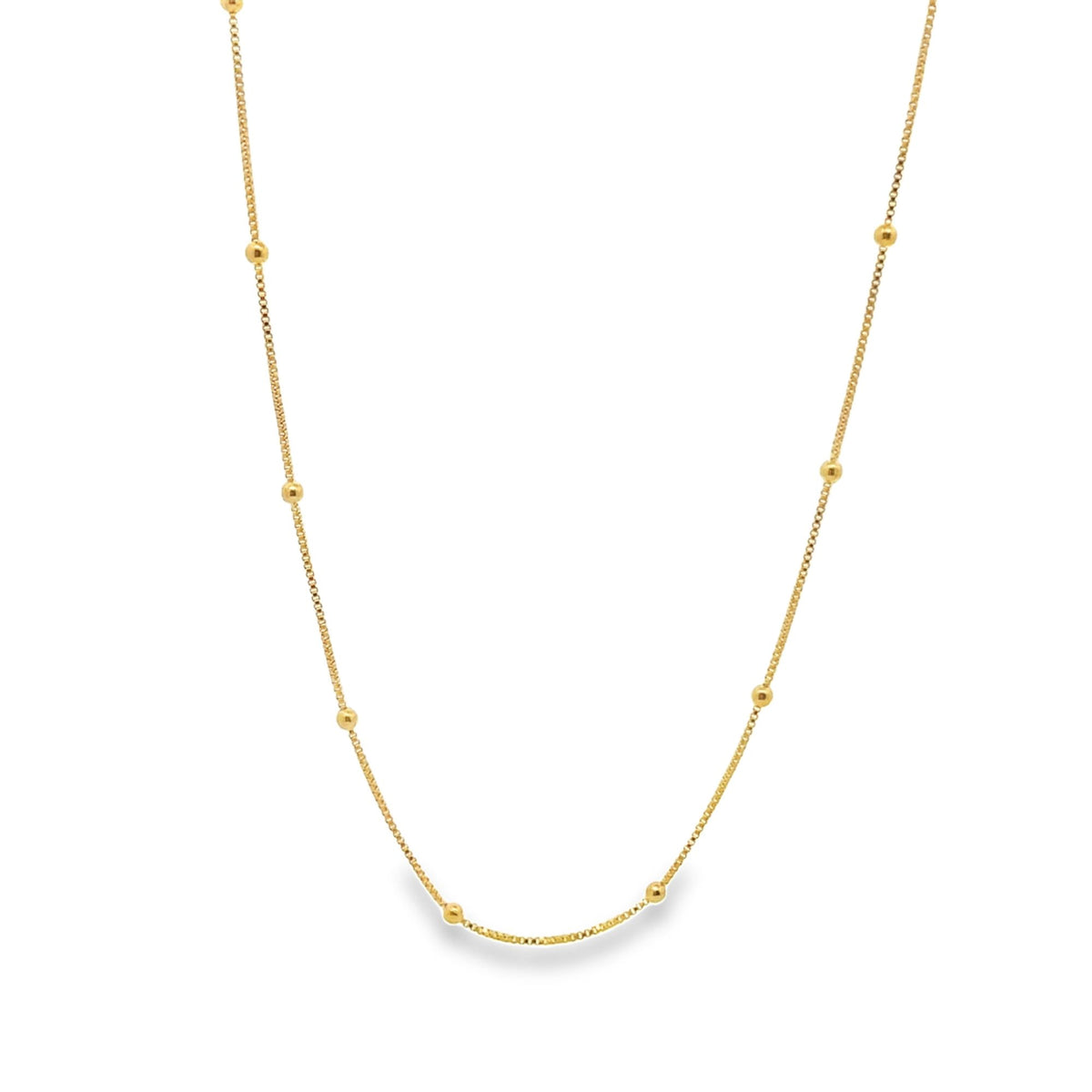 A delicate gold station necklace features evenly spaced metallic beads along a fine chain against a white background.
