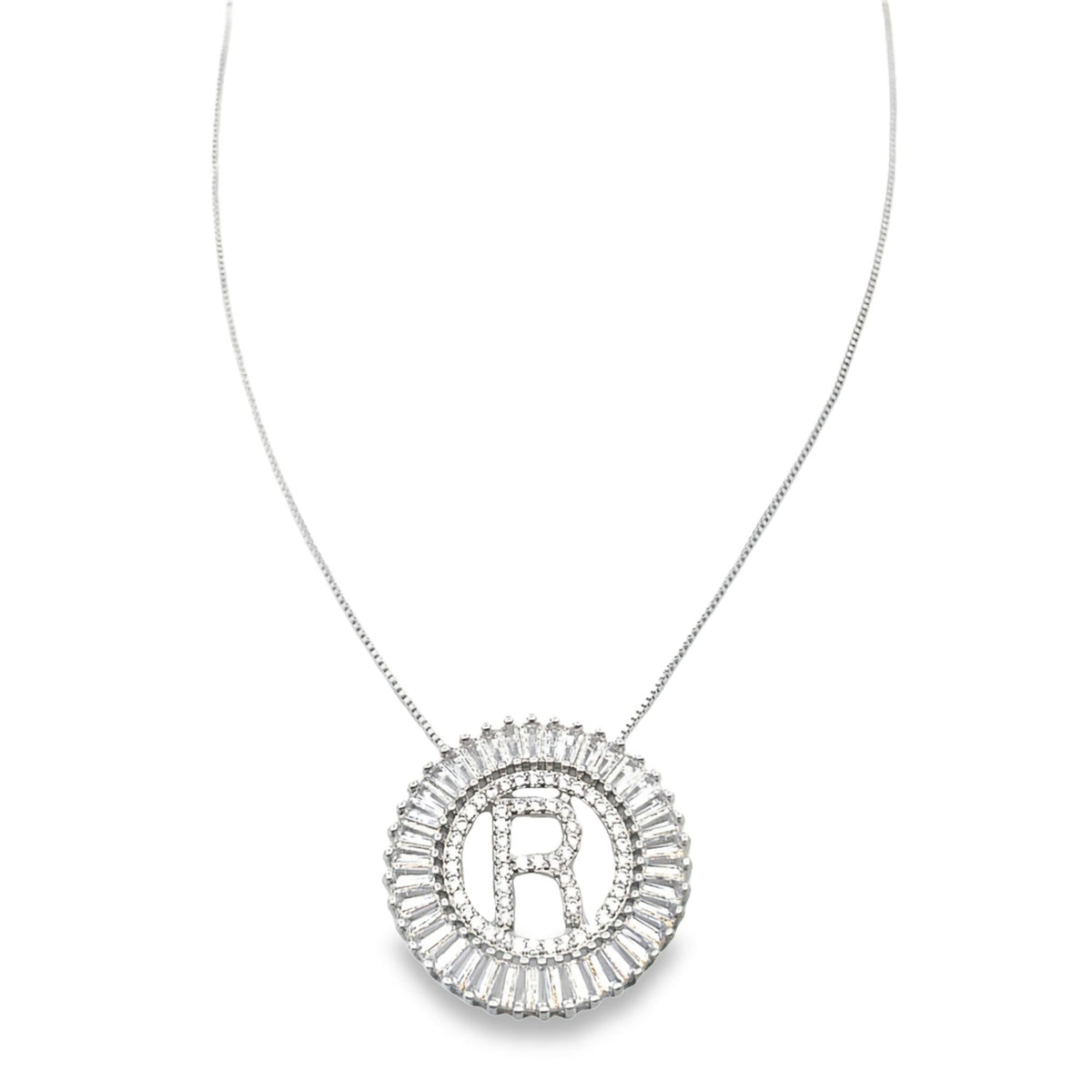 A delicate silver chain necklace features a round, diamond-encrusted pendant centered with the initial letter R.