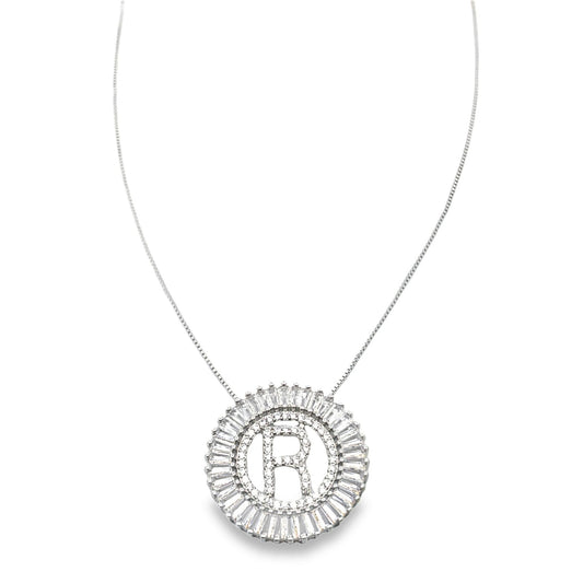 A silver chain necklace displays a round pendant featuring a sparkly letter R surrounded by a halo of baguette diamonds.