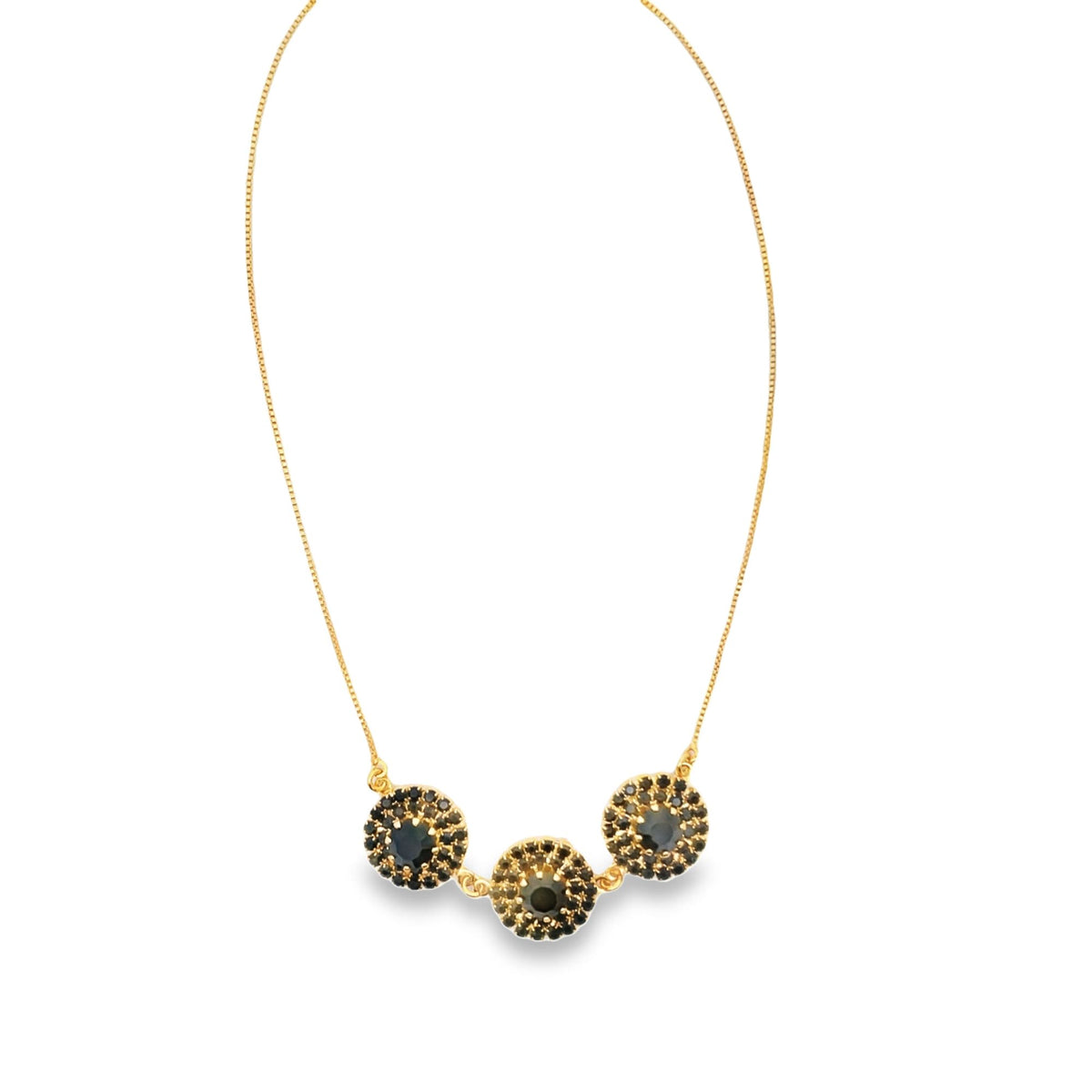 A delicate gold chain necklace dangles gracefully, showcasing three circular pendants encrusted with dark, sparkling gemstones against a clean white background.