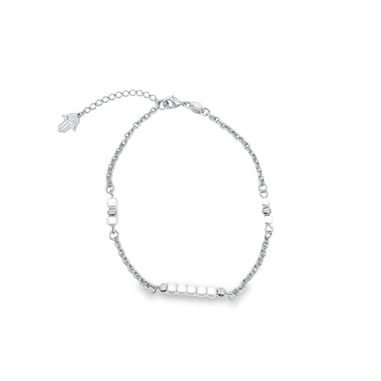 A delicate silver chain bracelet features a cluster of white pearls and metal beads, accented with a small Hamsa charm on the extension chain.