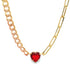 A gold chain necklace features a vibrant red heart-shaped gemstone pendant suspended at its center.