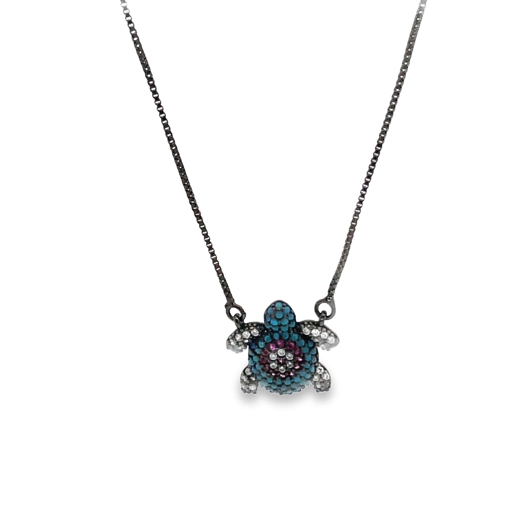 A delicate silver chain necklace features a sparkling sea turtle pendant adorned with turquoise, purple, and white crystals.