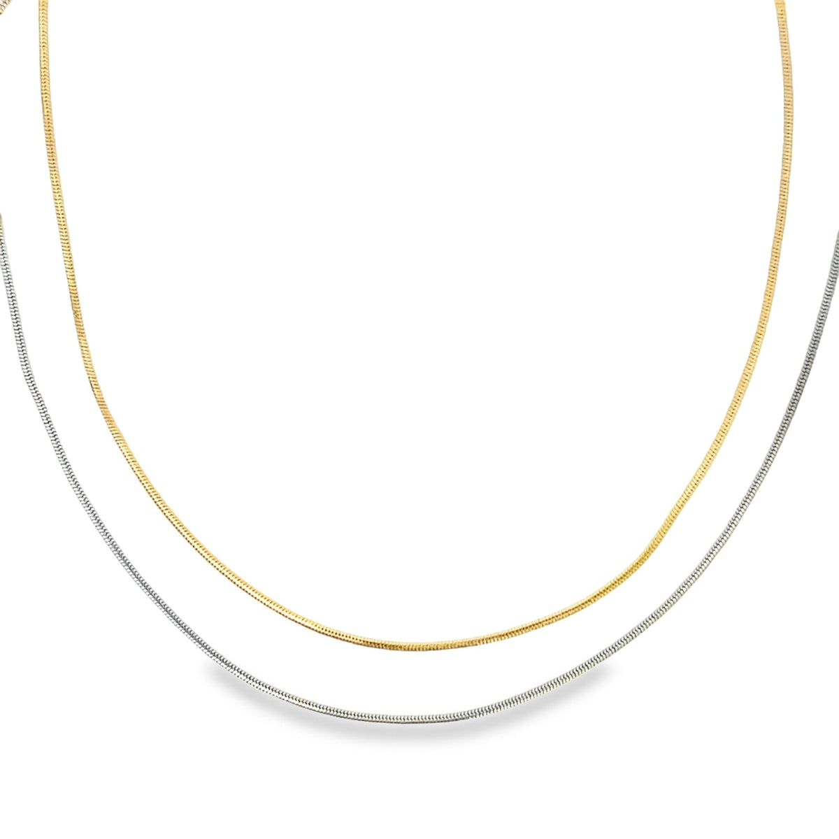 A gold chain and a silver chain lie gracefully against a clean white background.