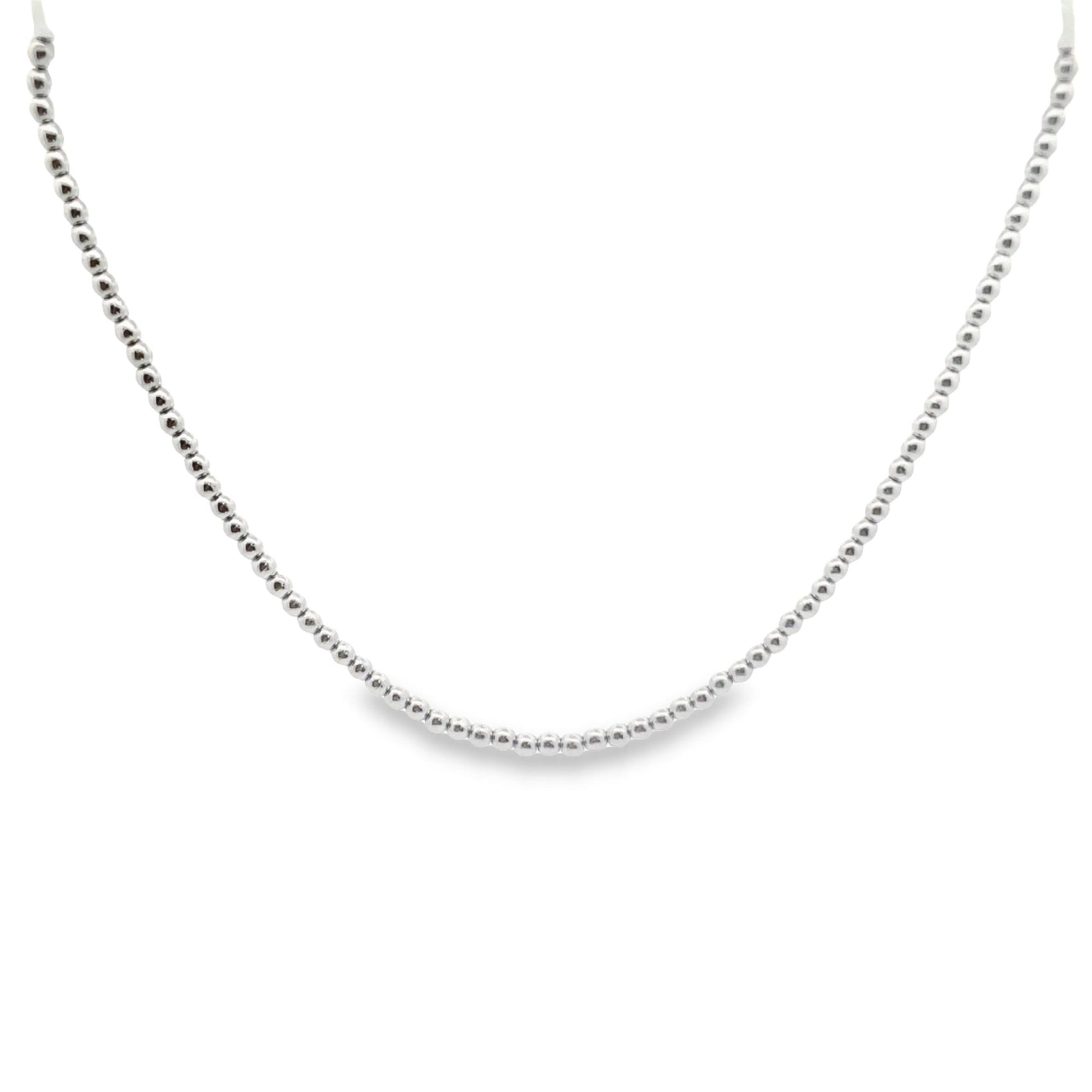 A delicate silver beaded chain necklace curves gracefully against a clean white background.