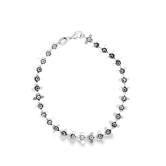 A sterling silver charm bracelet featuring a continuous chain of interconnected flower-shaped links lies displayed against a clean white background.