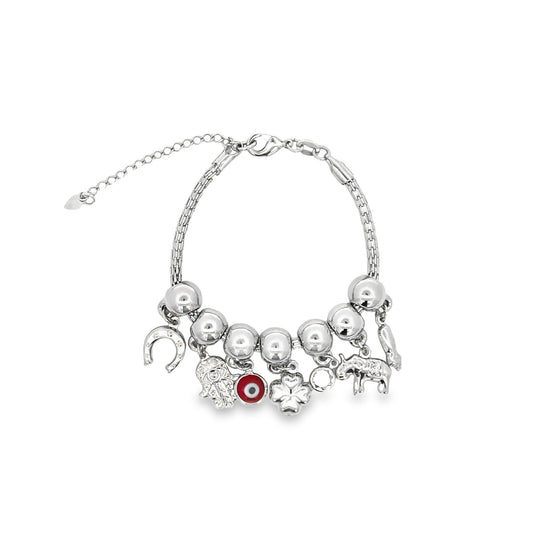 A silver charm bracelet features dangling symbols including a horseshoe, Hamsa hand, red evil eye, clover, and elephant against a white background.