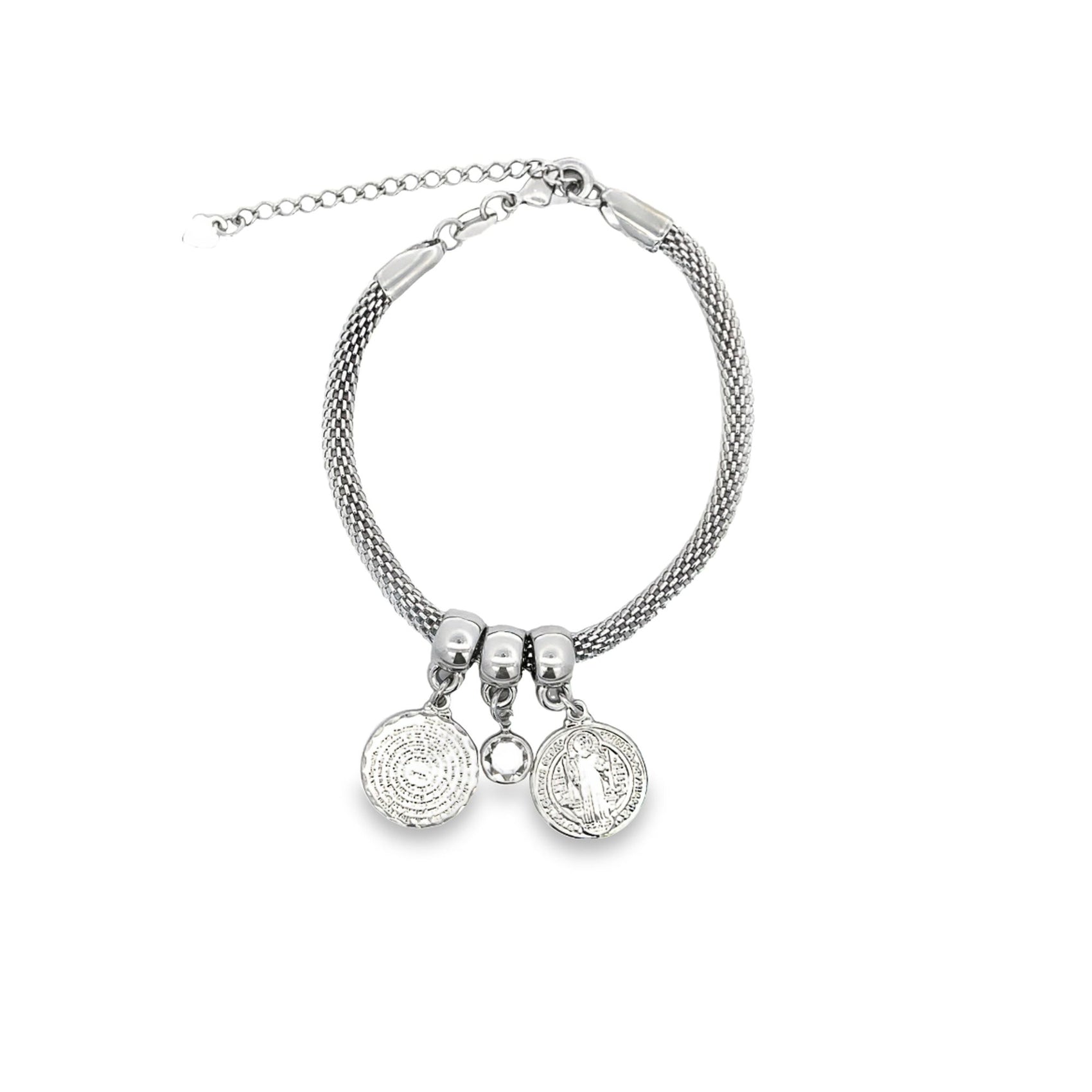 A silver mesh charm bracelet features two round religious medals and a sparkling gemstone pendant against a plain white background.