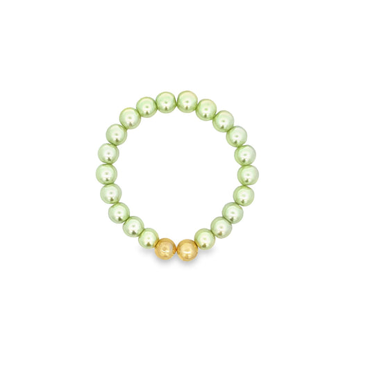 A beaded stretch bracelet features light green pearls accented by two shiny gold spheres at the bottom.