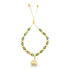 A gold bolo bracelet features alternating green and gold beads with a dangling elephant charm against a white background.