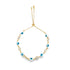 A delicate gold adjustable bolo bracelet features alternating blue and white evil eye beads and sparkling cubic zirconia stones against a white background.