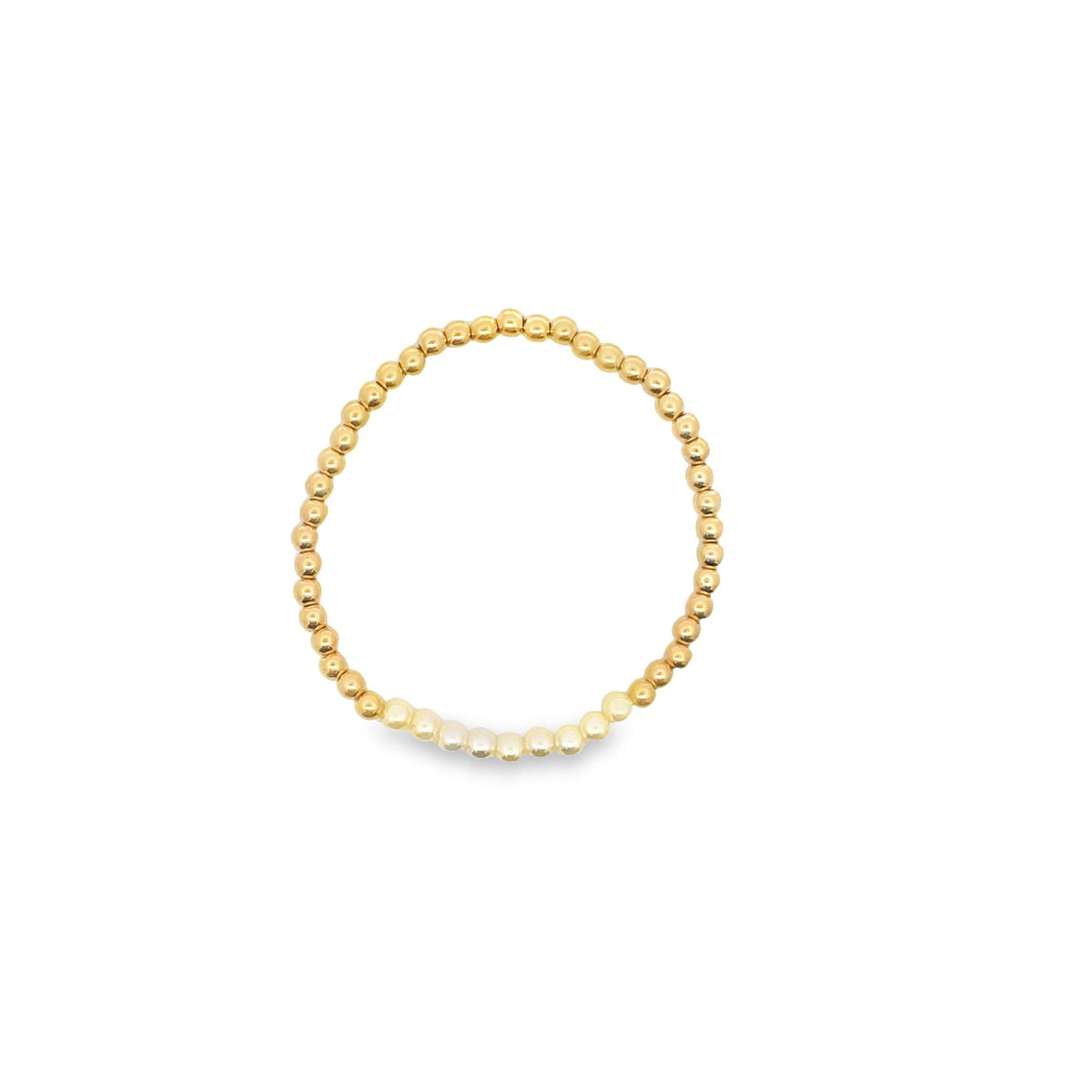 A delicate gold beaded stretch bracelet features a subtle cluster of white seed beads at the bottom against a plain white background.