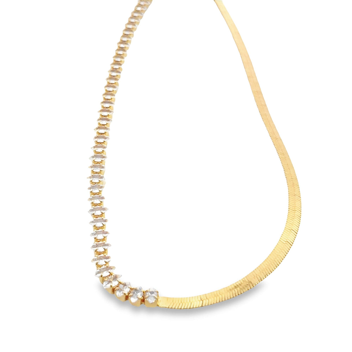 A gold dual-sided necklace features a row of sparkling diamond-like stones on one half and a sleek herringbone chain on the other.
