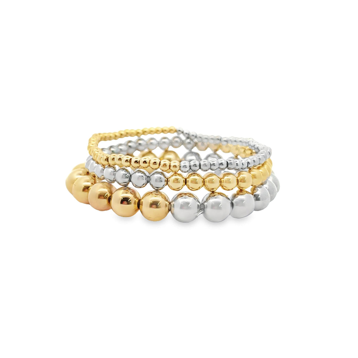 A stack of mixed gold and silver ball bead stretch bracelets rests on a white background.