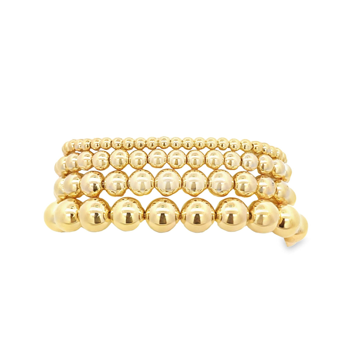 A stack of four graduated gold ball bead bracelets gleams against a clean white background.