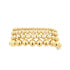 A stack of four graduated gold ball bead bracelets gleams against a clean white background.