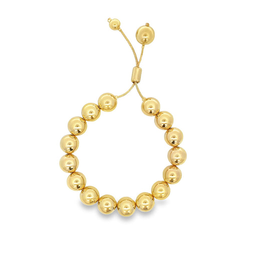 A polished gold ball bead bracelet features an adjustable sliding closure with dangling beaded cords.