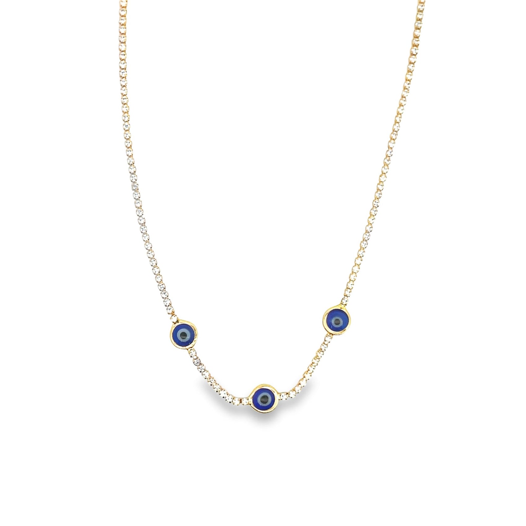 A delicate gold tennis necklace adorned with three blue evil eye charms hangs against a white background.