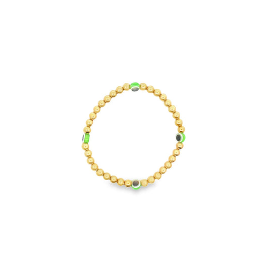 A delicate gold bead bracelet features interspersed green evil eye charms against a clean white background.