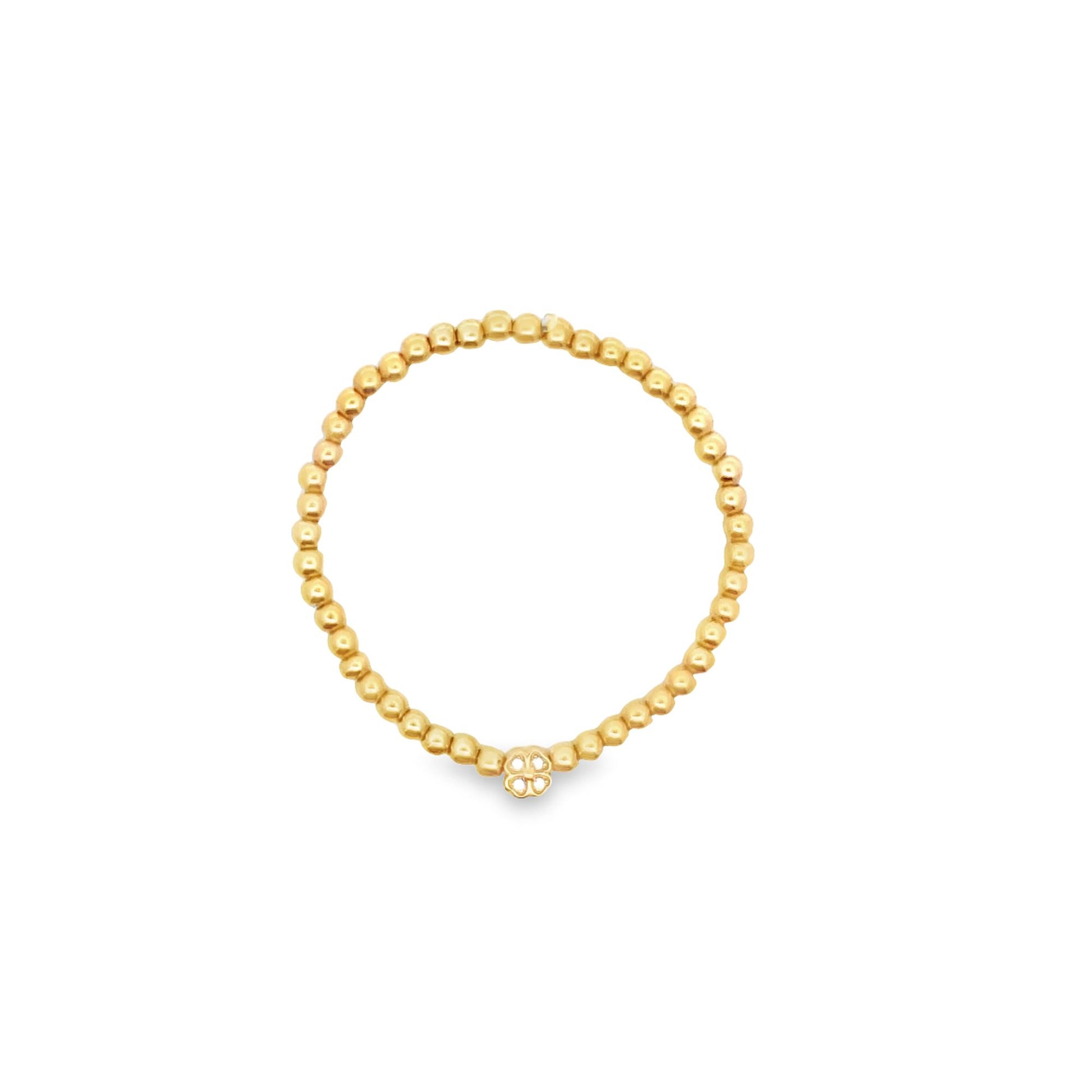 A delicate gold bead stretch ring features a small clover-shaped charm on a plain white background.