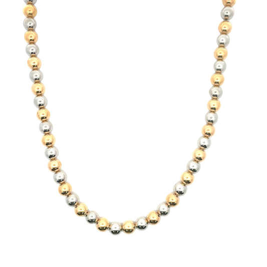 A two-tone gold and silver beaded necklace sparkles against a plain white background.