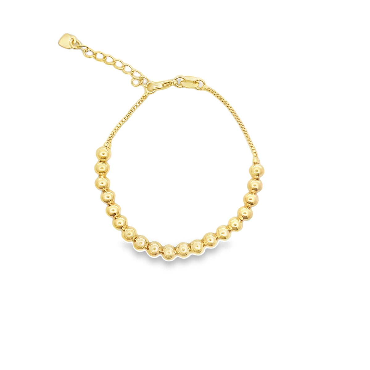A gold bead bracelet with an adjustable chain and a tiny heart charm rests against a white background.