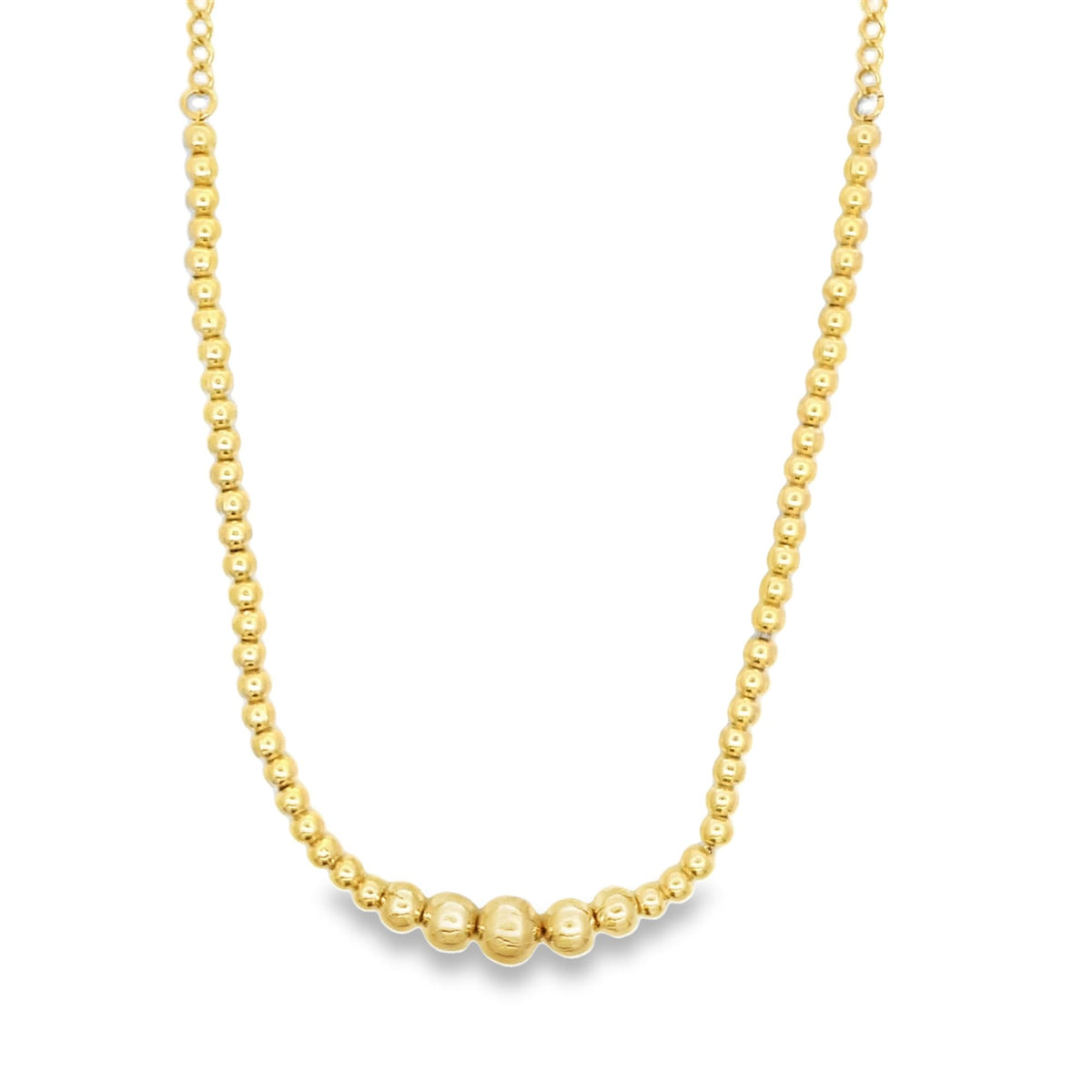 A delicate gold beaded necklace features a graduated design with larger spheres resting at the center.