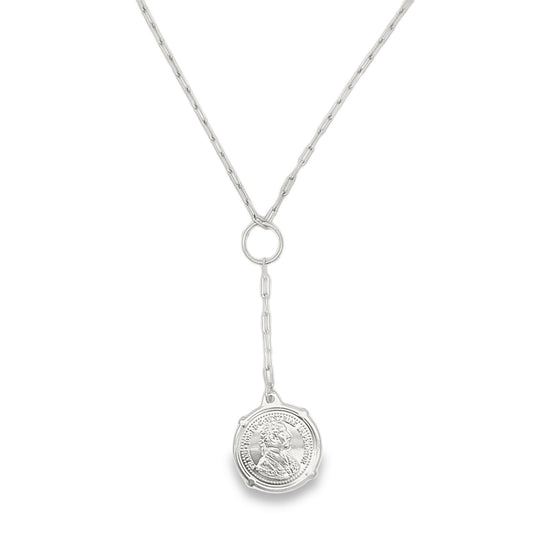 A silver lariat necklace features a delicate chain passing through a circular ring to suspend a detailed coin pendant.