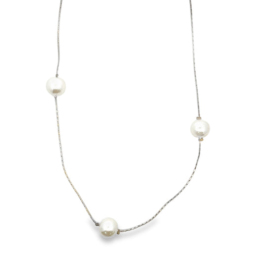 A delicate silver chain necklace features three spaced white pearls against a clean white background.