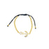 A gold anchor charm bracelet with glittering pavé diamonds features shiny metal beads along a black adjustable cord.