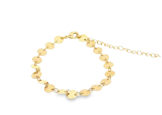 A delicate gold disc bracelet rests on a white background, featuring a chain of small, shimmering coin charms.