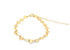 A delicate gold disc bracelet rests on a white background, featuring a chain of small, shimmering coin charms.