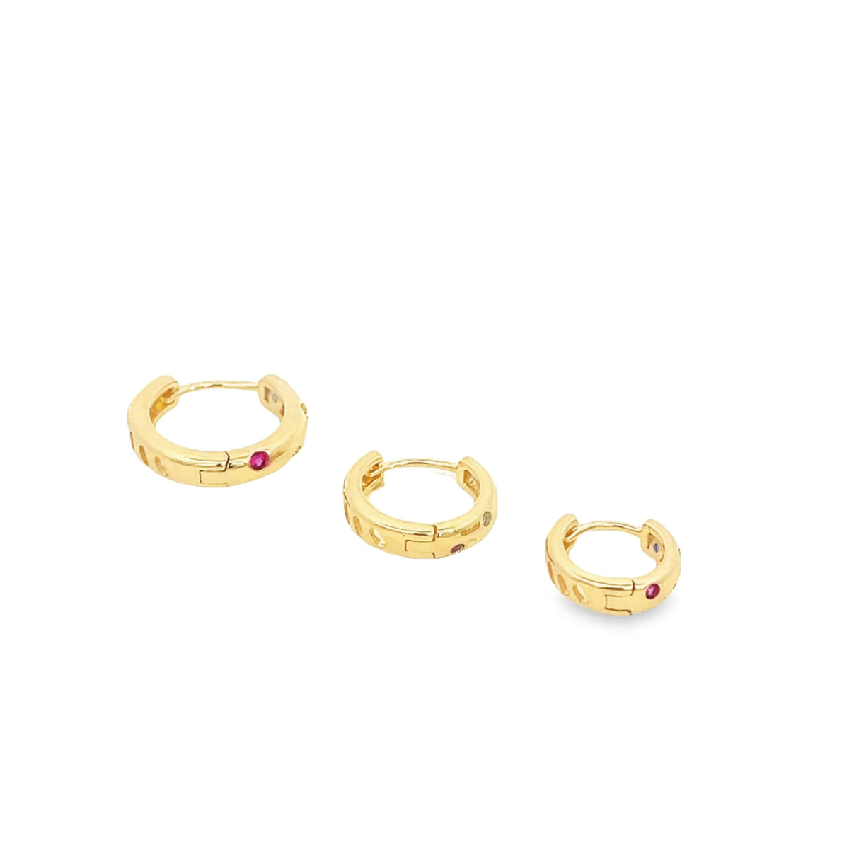Three graduated gold hoop earrings featuring embedded red and clear gemstones sit arranged diagonally on a plain white background.