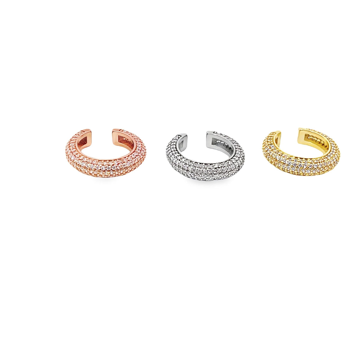Three shimmering pavé ear cuffs in rose gold, silver, and yellow gold rest neatly in a row against a clean white background.
