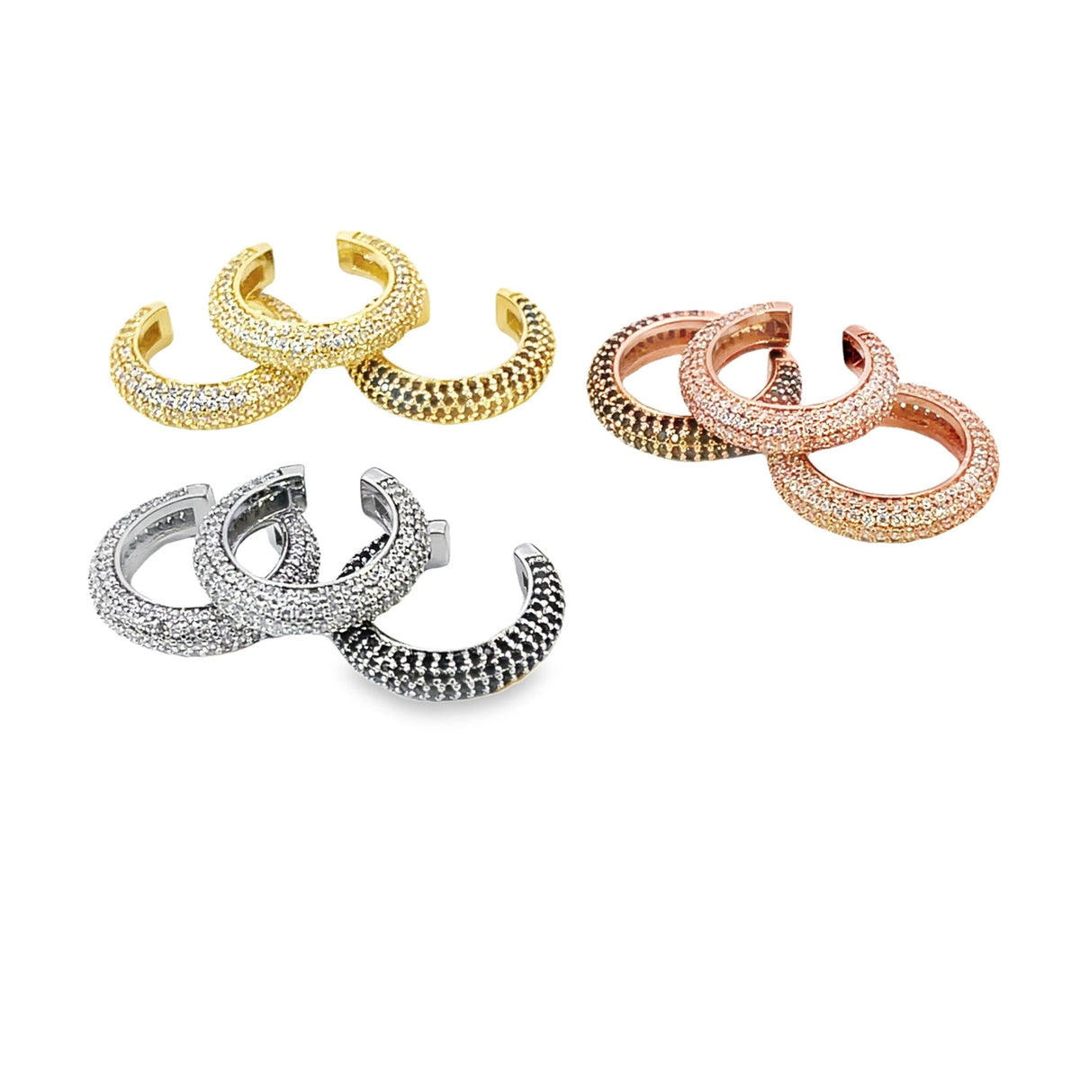 Three sets of pavé-set huggie hoop earrings in yellow gold, rose gold, and silver display sparkling crystal details against a white background.