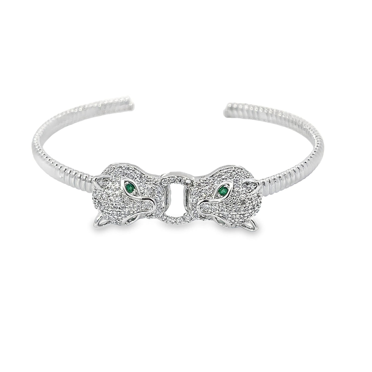 A silver pave diamond panther cuff bracelet features two facing leopard heads embellished with green emerald eyes against a clean white background.