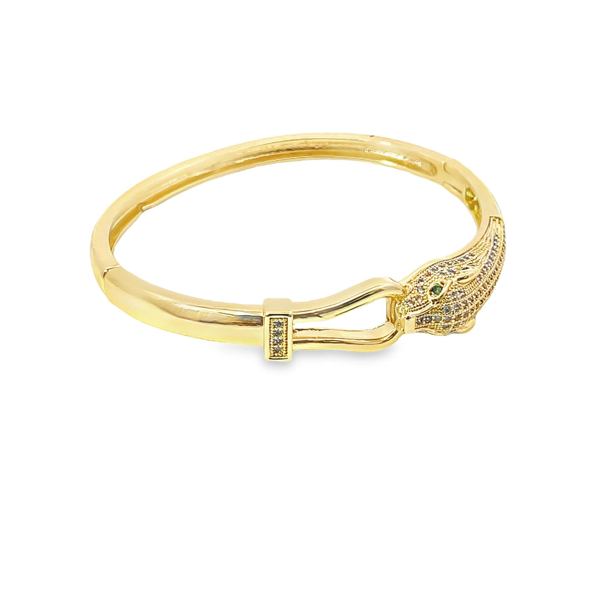 A gold snake bracelet features sparkling crystal pave accents and distinctive green gemstone eyes.