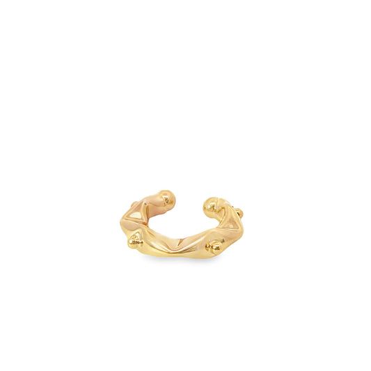 A thick, polished gold ear cuff features an irregular, textured design with small spherical accents against a clean white background.