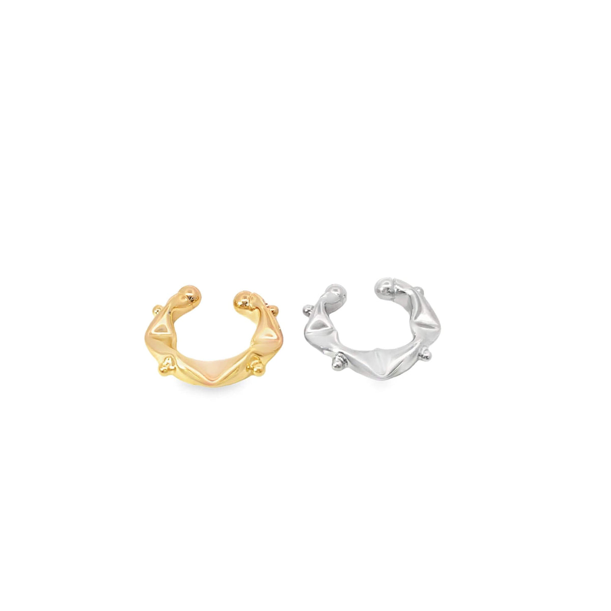 Two abstract, organic-shaped ear cuffs in polished gold and silver sit side by side against a white background.