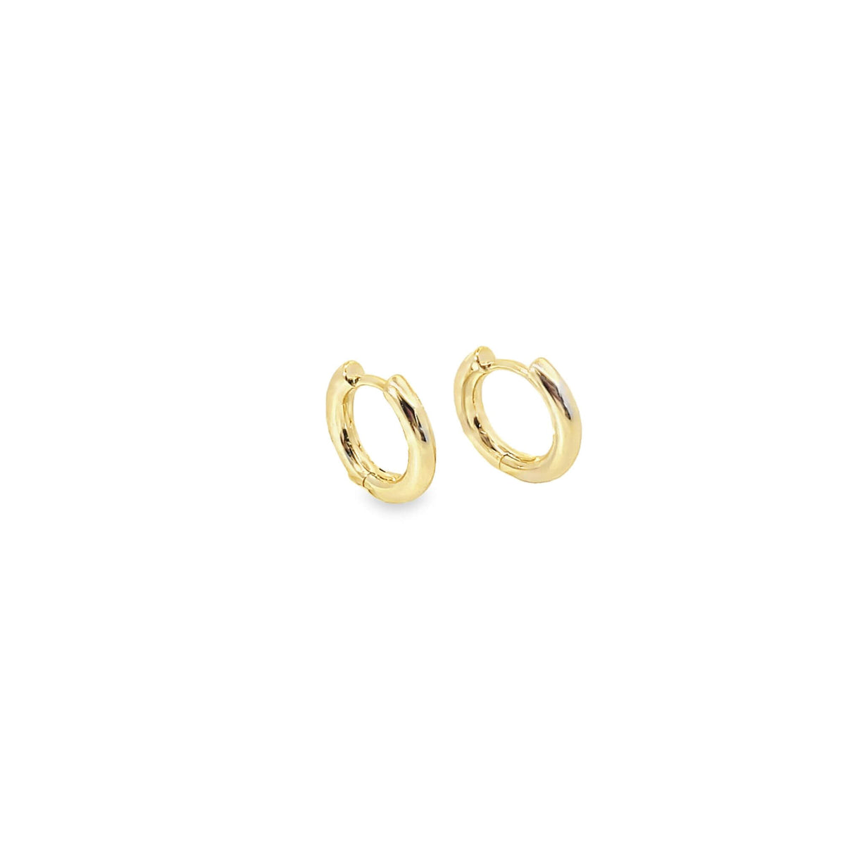 A pair of small gold huggie hoop earrings rests against a clean white background.